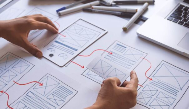 Frontier Restoration | Rsm Marketing Person working on website design prototypes with drawn diagrams and a laptop, representing expert seo and online advertising for hvac marketing agency.